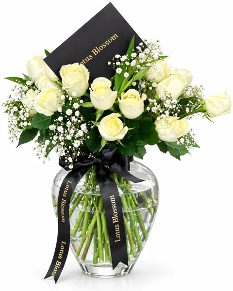 Ivory roses in a glass vase, tied with the brand's black ribbon